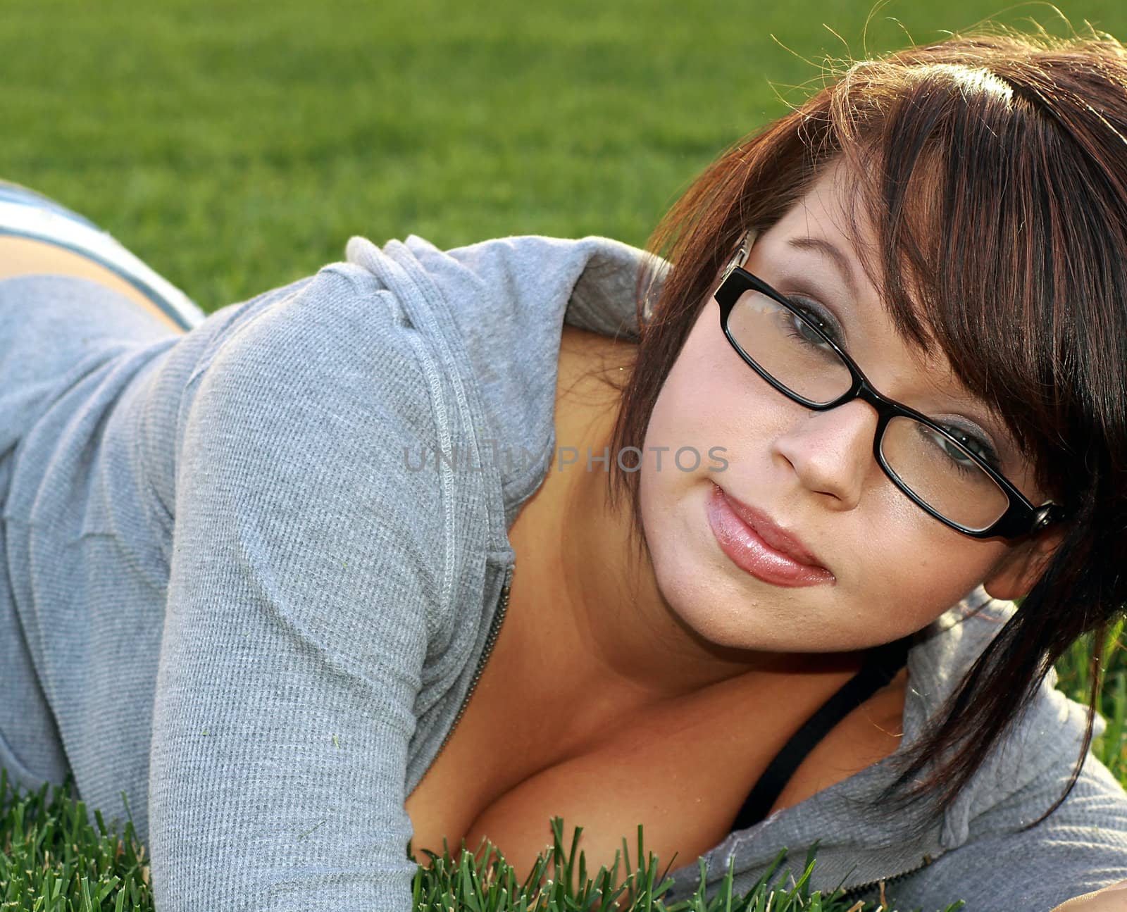 Beautiful model with blue eyes and glasses laying in the grass