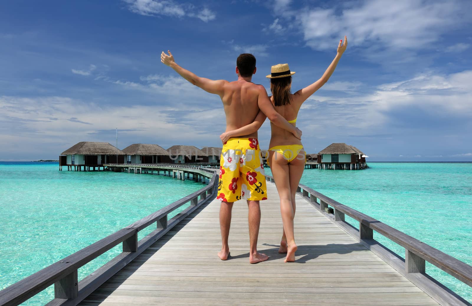 Couple on a tropical beach jetty at Maldives