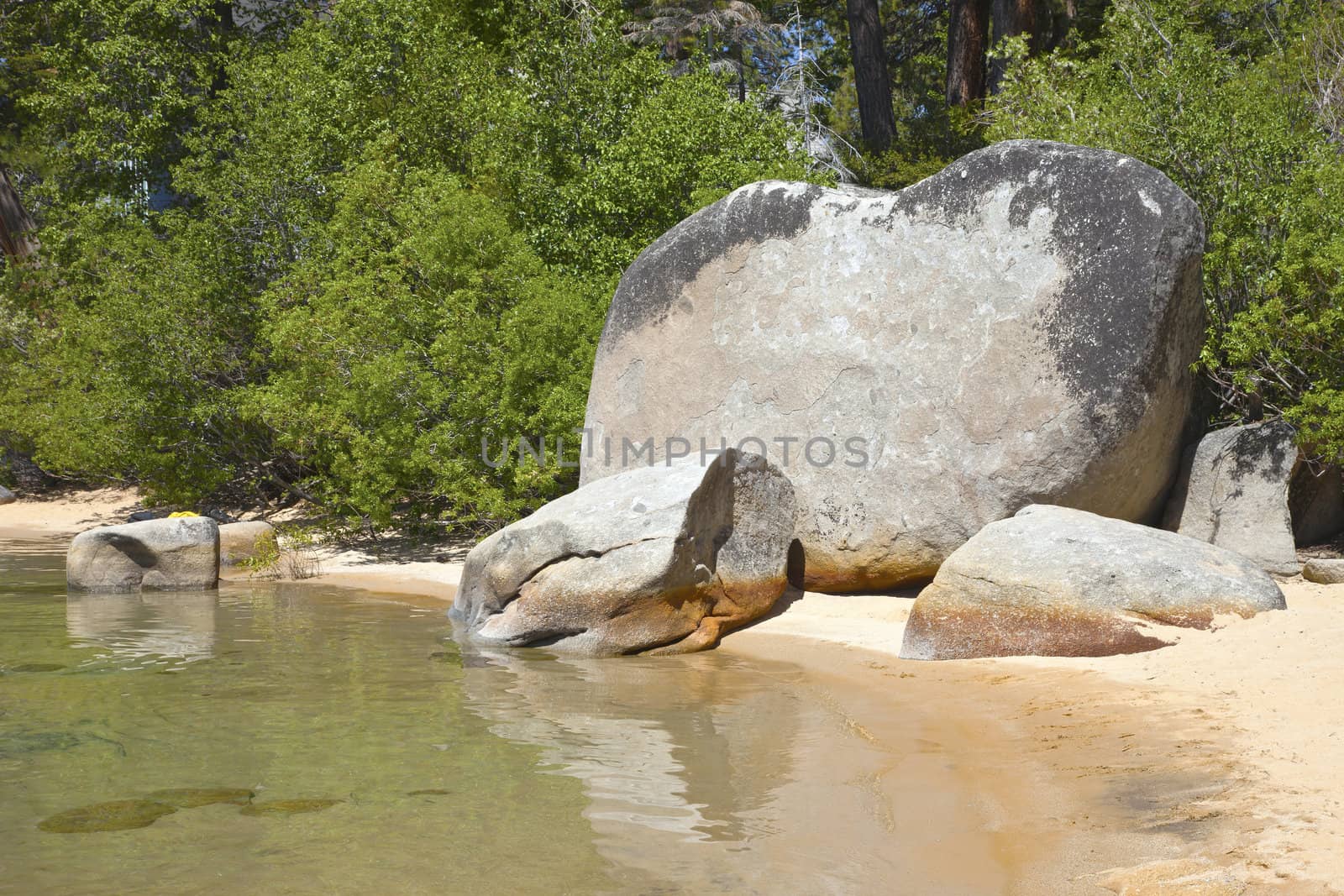 Large rock and rocks on a beach on lake Tahoe California.
