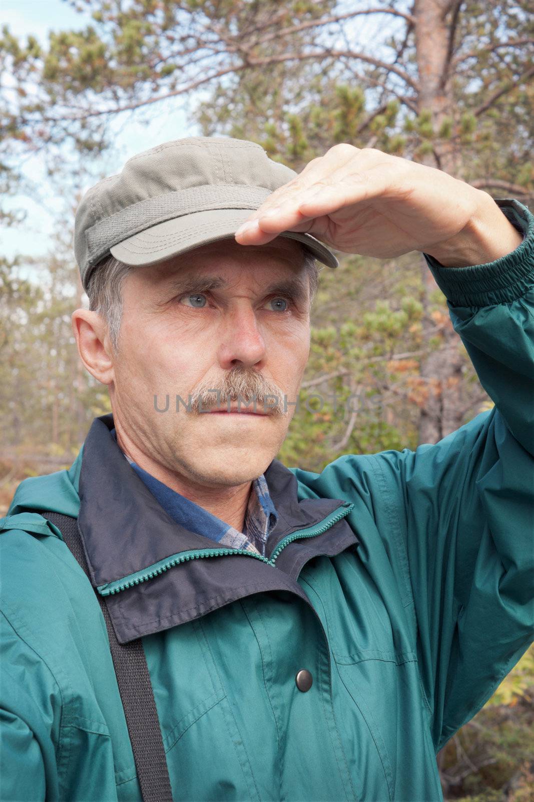 An elderly traveller looking into the distance in an autumn wood