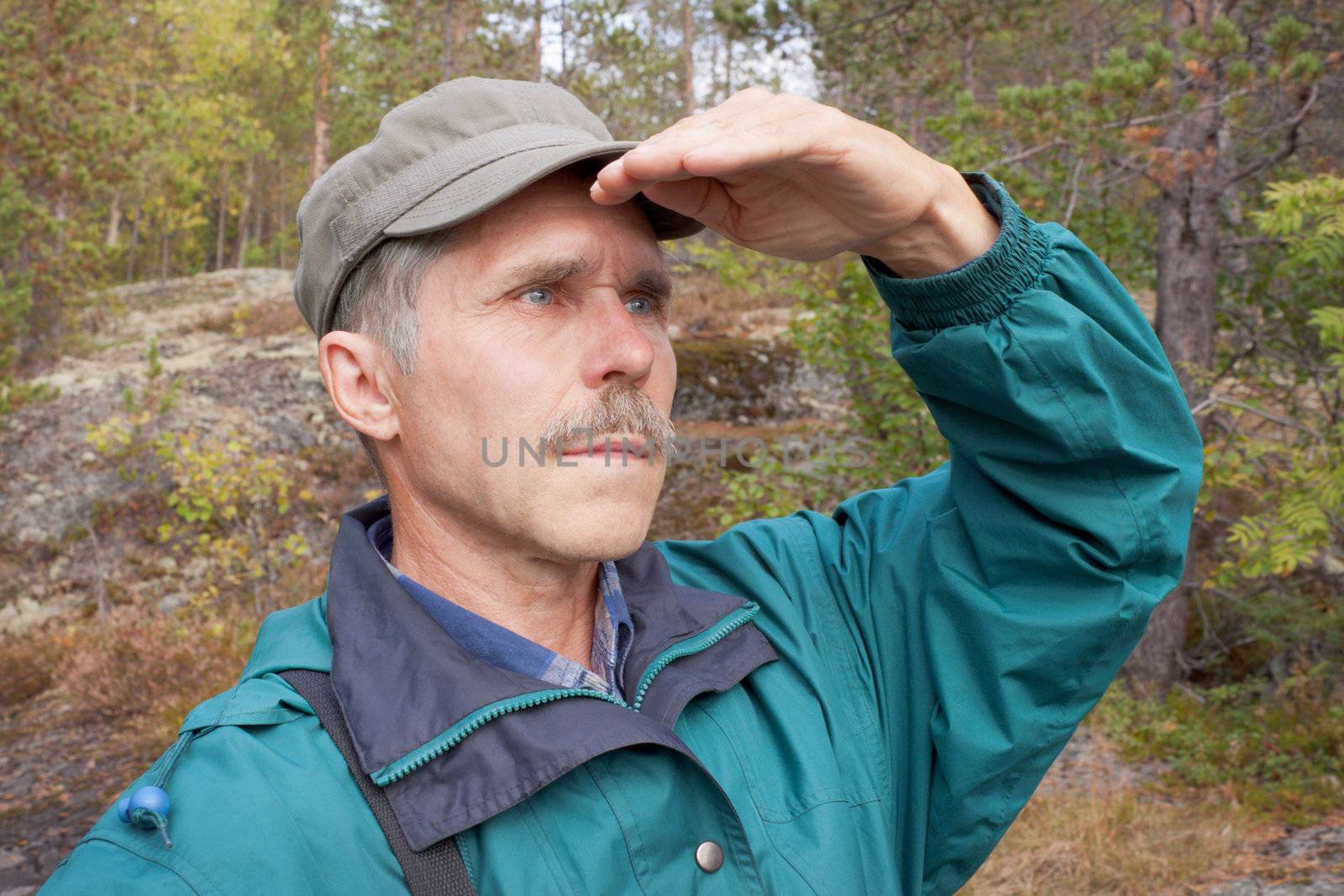 An elderly traveller looking into the distance in an autumn wood