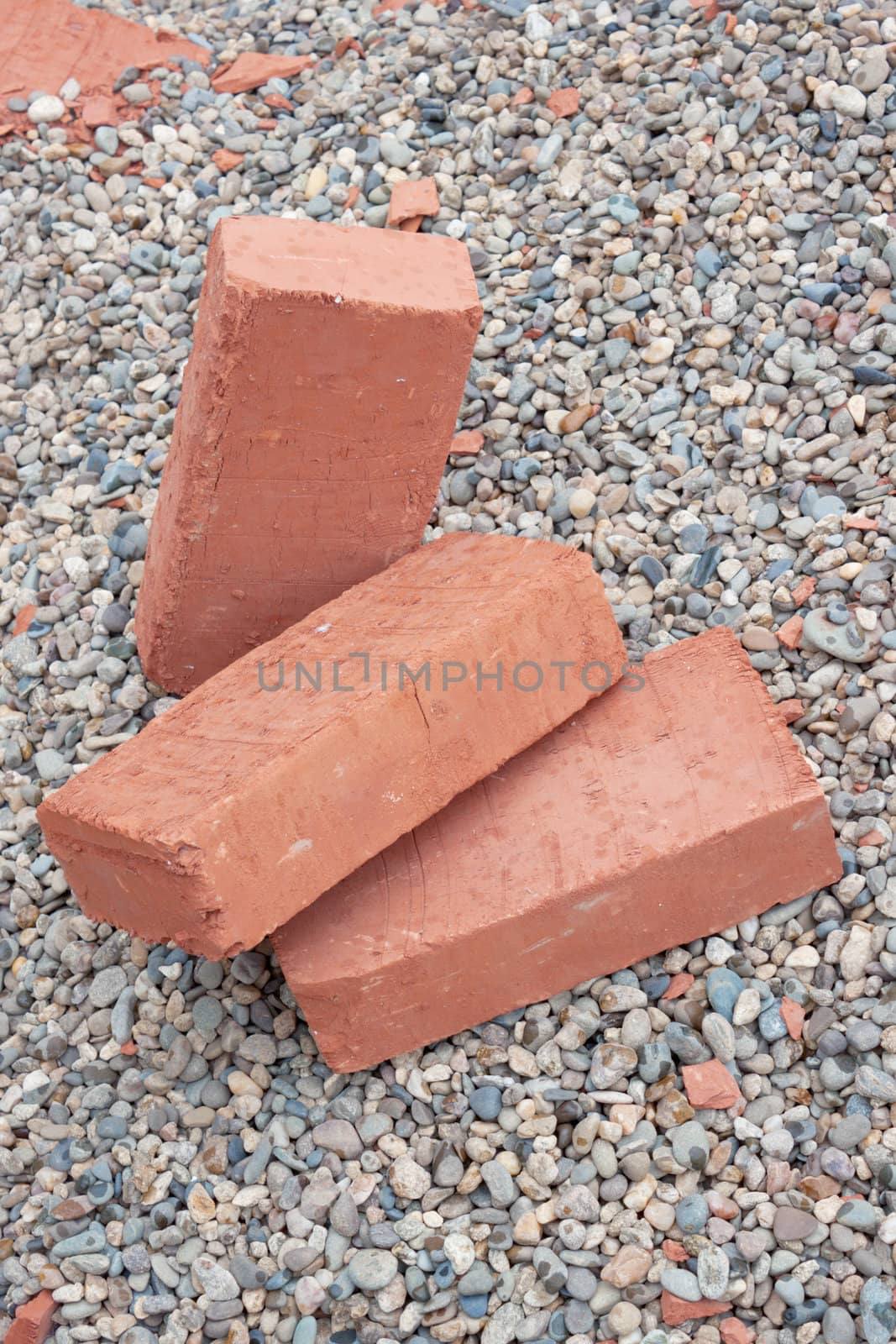 Three red clay bricks lying on the gravel