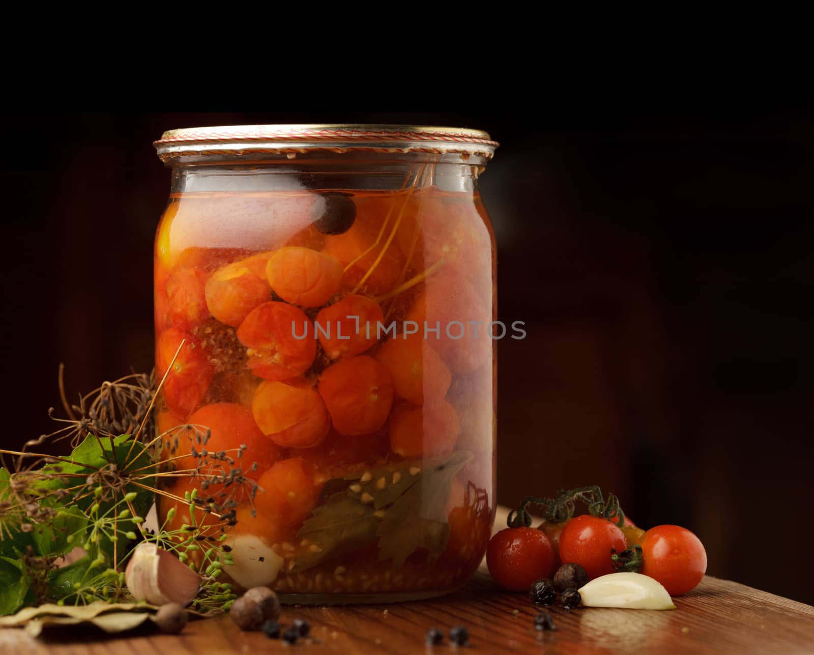 Still life of preserving tomatoes on wooden table in kitchen