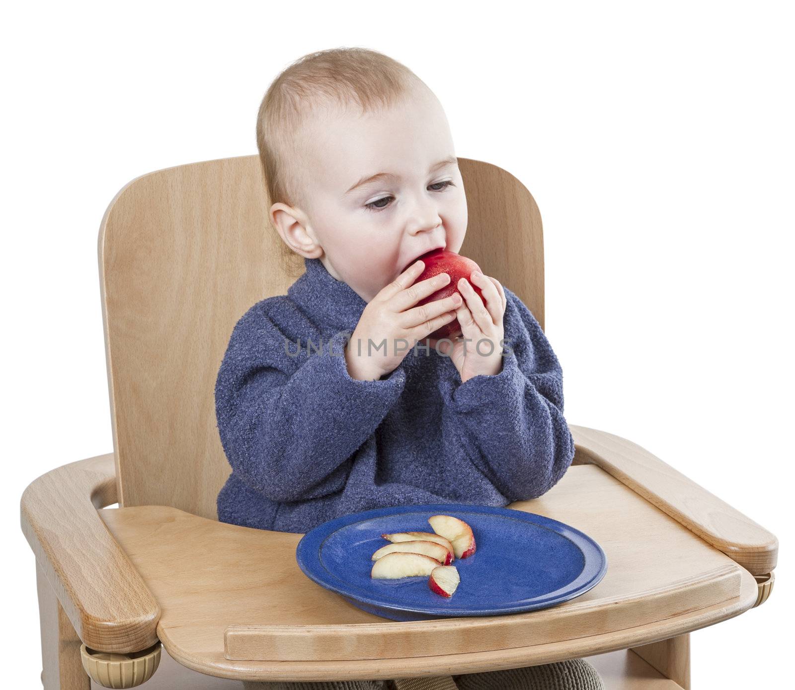 young child eating peaches in high chair by gewoldi