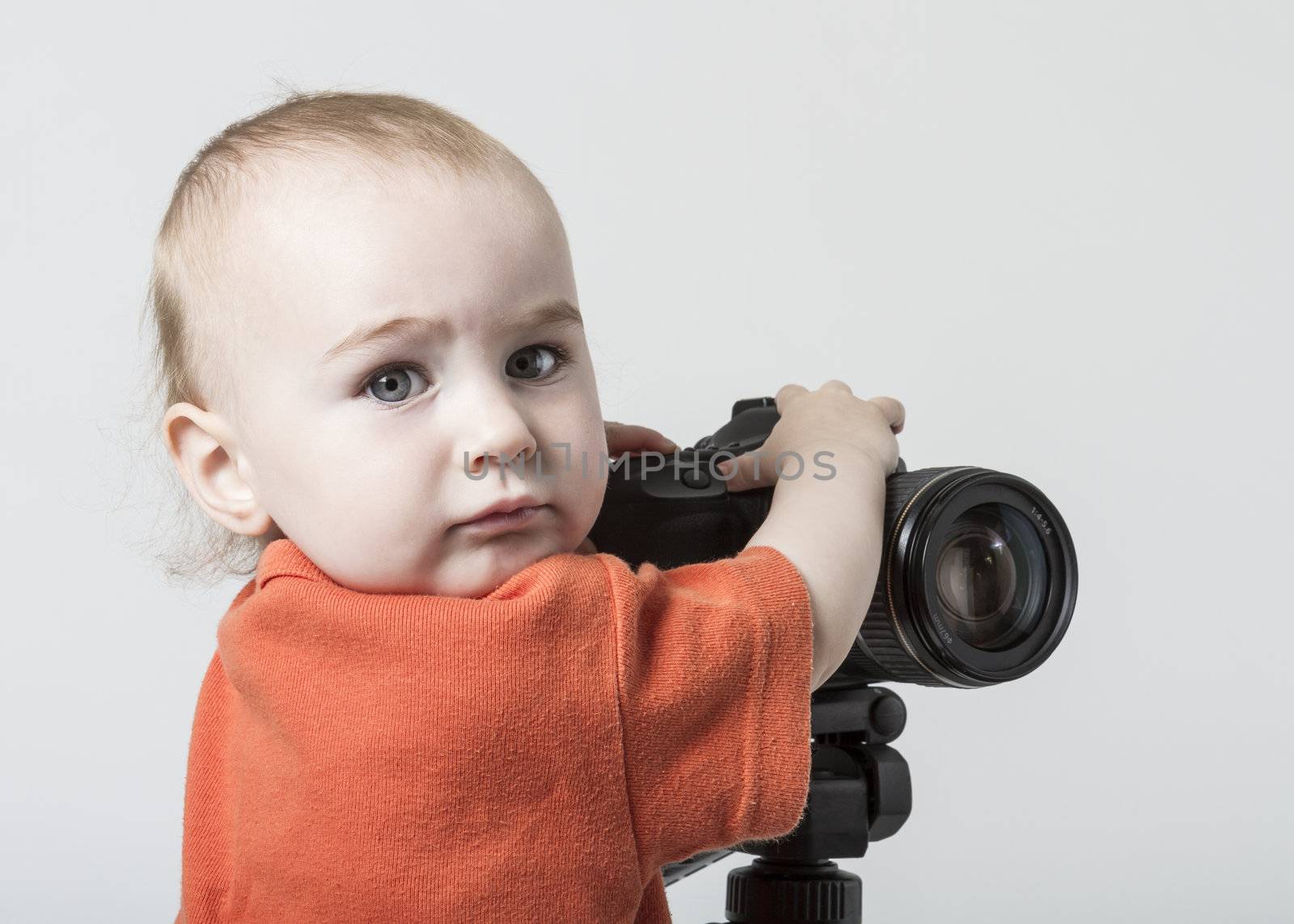 young child with digital SLR camera on grey background