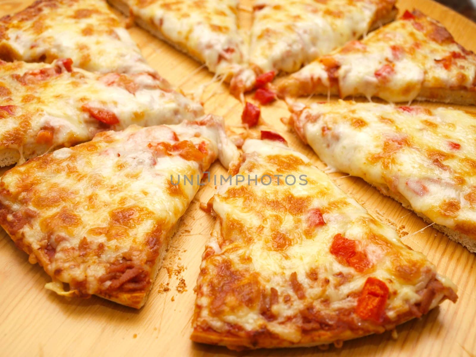 Sliced fresh pizza with red pepper on wooden board