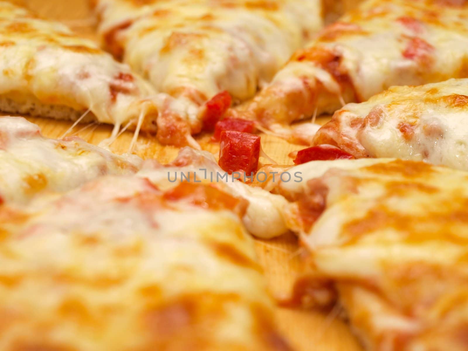 Sliced fresh pizza with red pepper on wooden board by Arvebettum