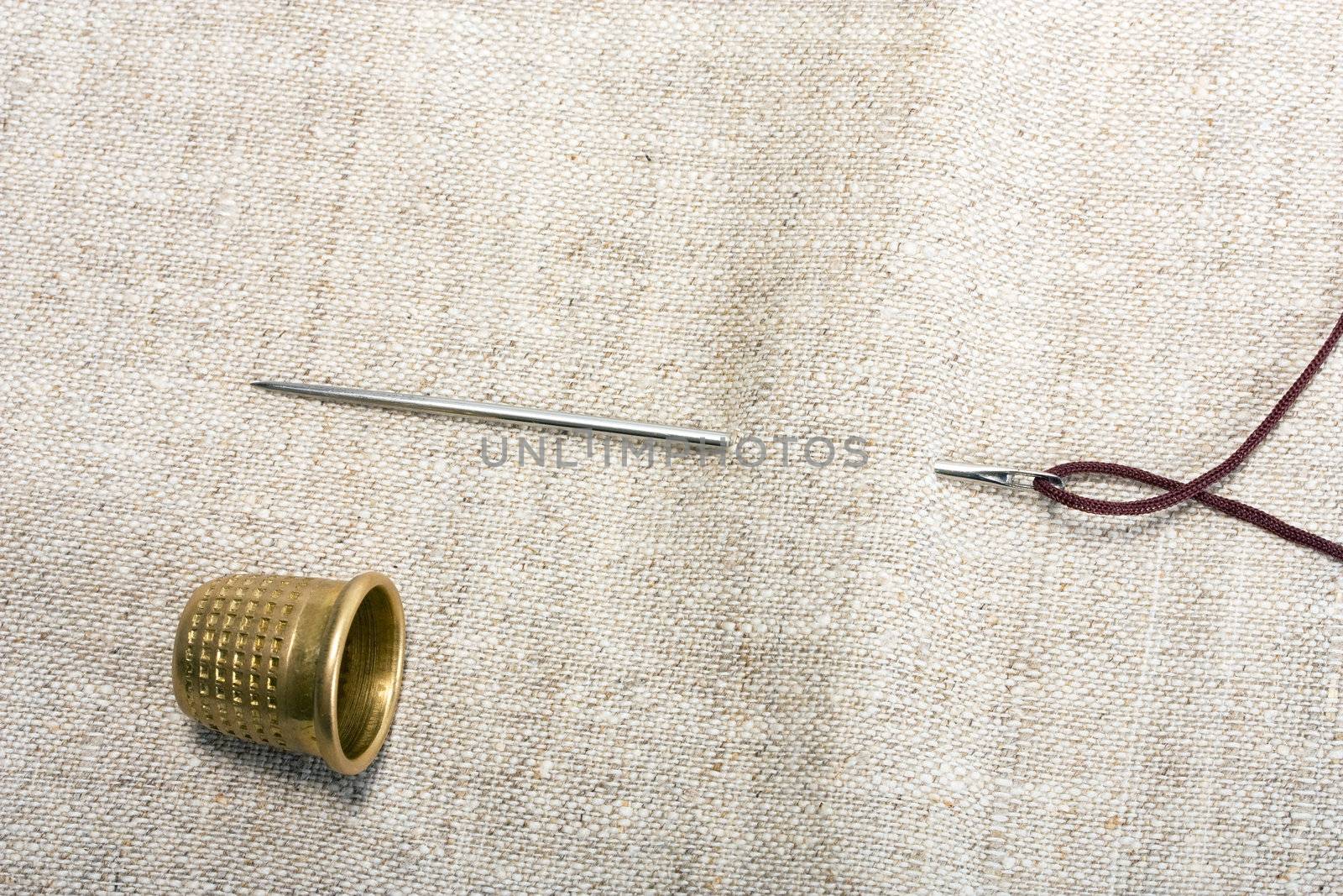 needle , thimble and thread on background fabrics concept