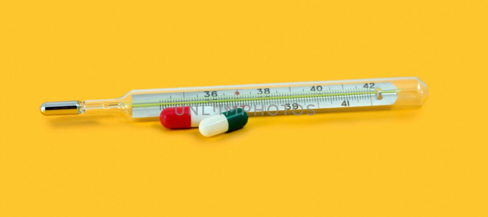 thermometer with pill isolated on yellow background