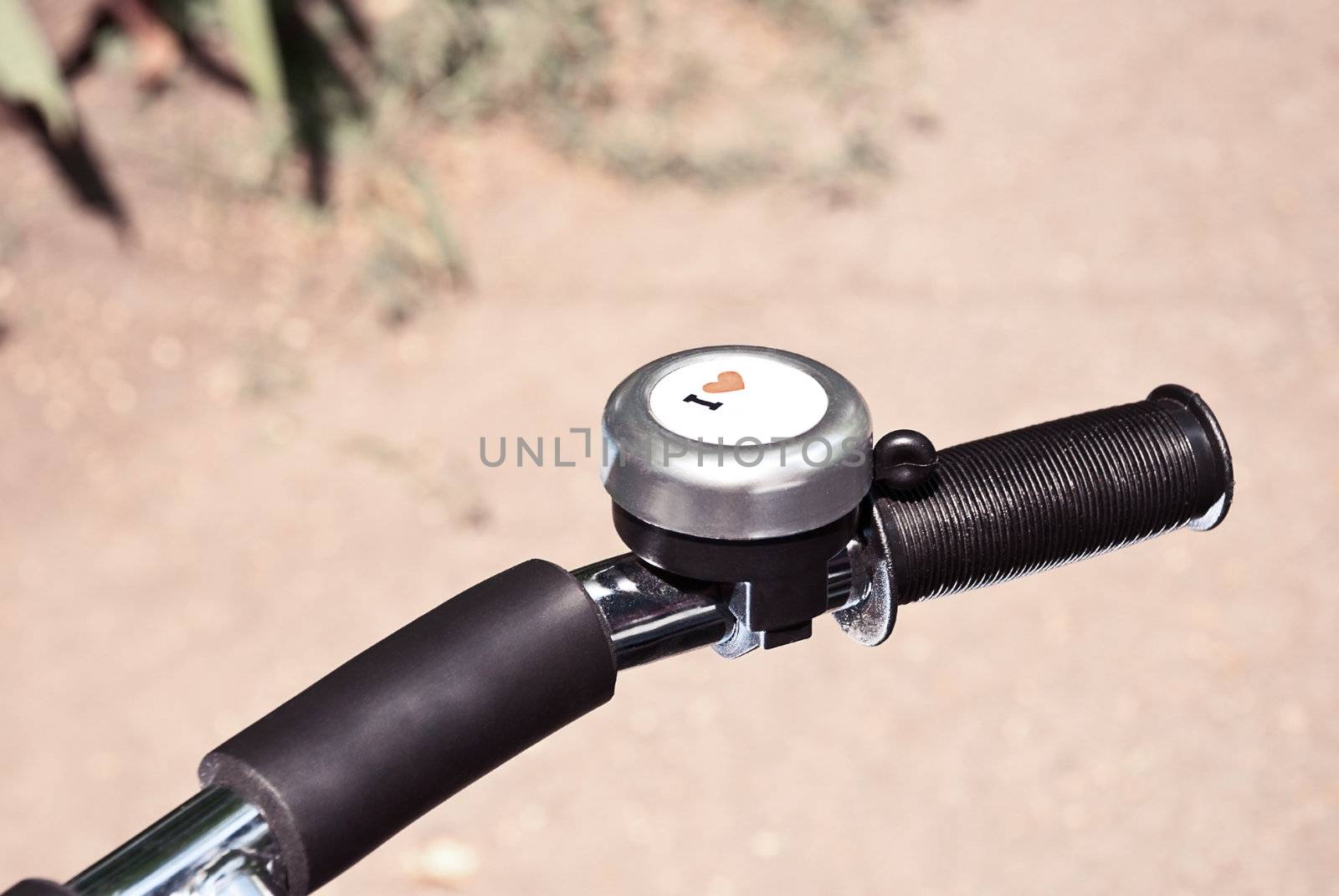 Bicycle handle with signal bell with symbol "I love" closeup.