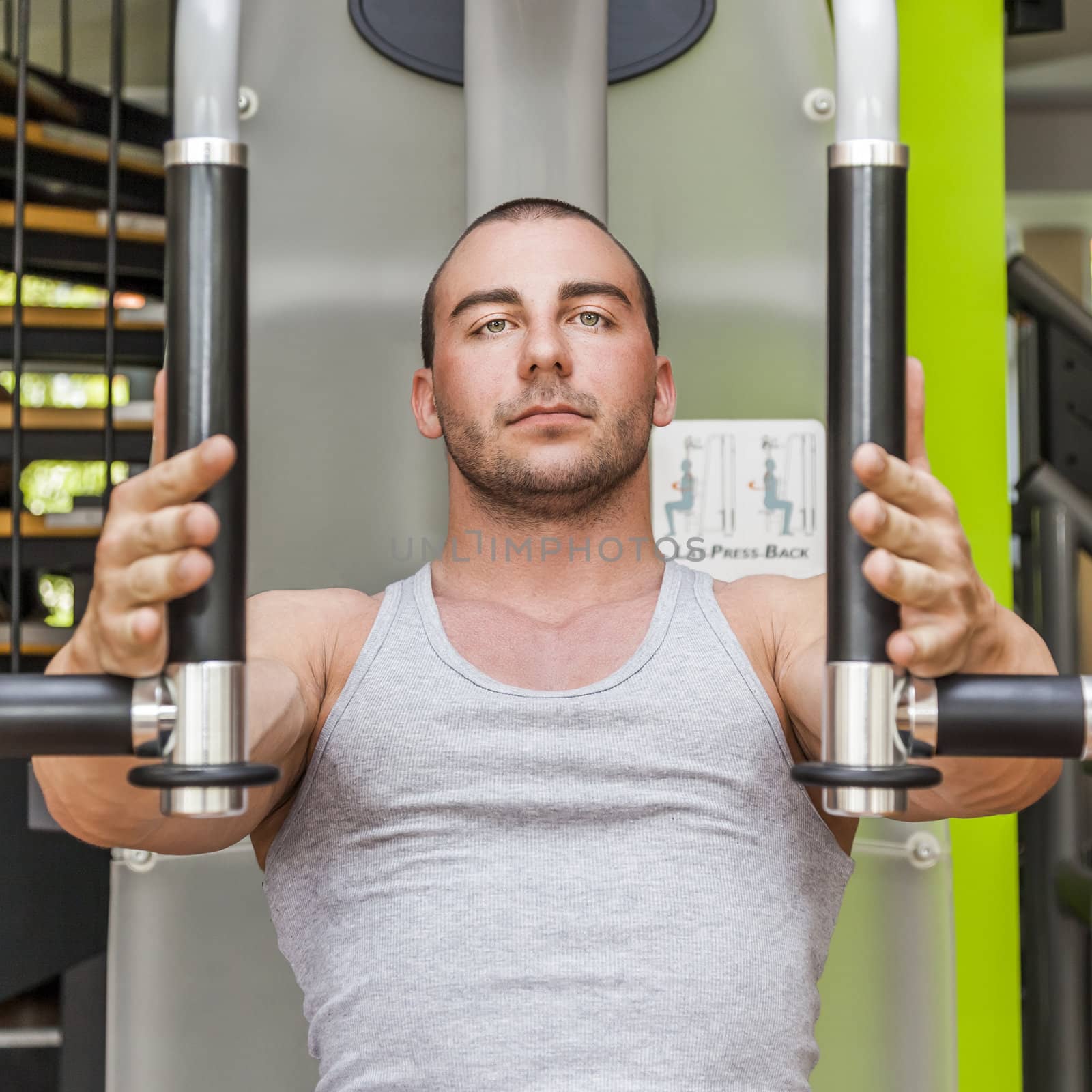 An image of a muscular male on a butterfly machine in gym