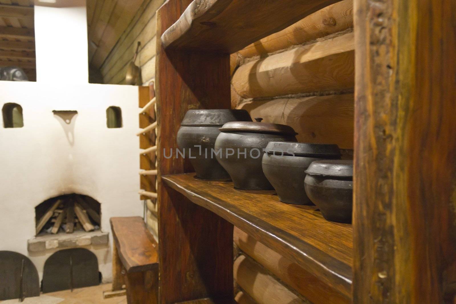 Interior of Russian log hut with the furnace and pots