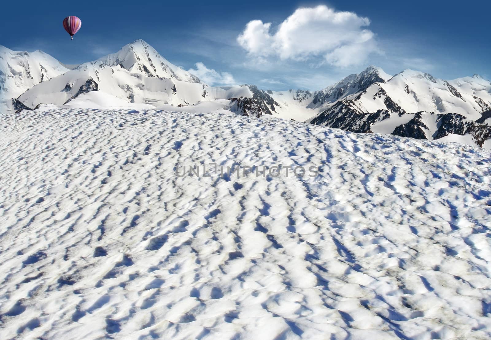 Mountain landscape: snowfield with mountains and glaciers and hot air balloon flying in the sky