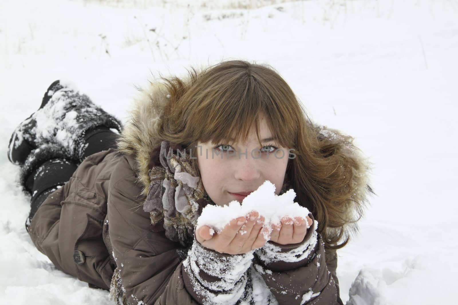 The beautiful girl lays with snow in hands by tanu666a