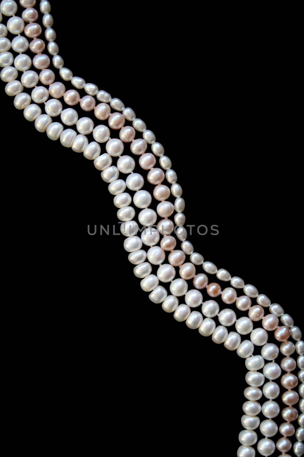 White and pink pearls on the black silk as background 