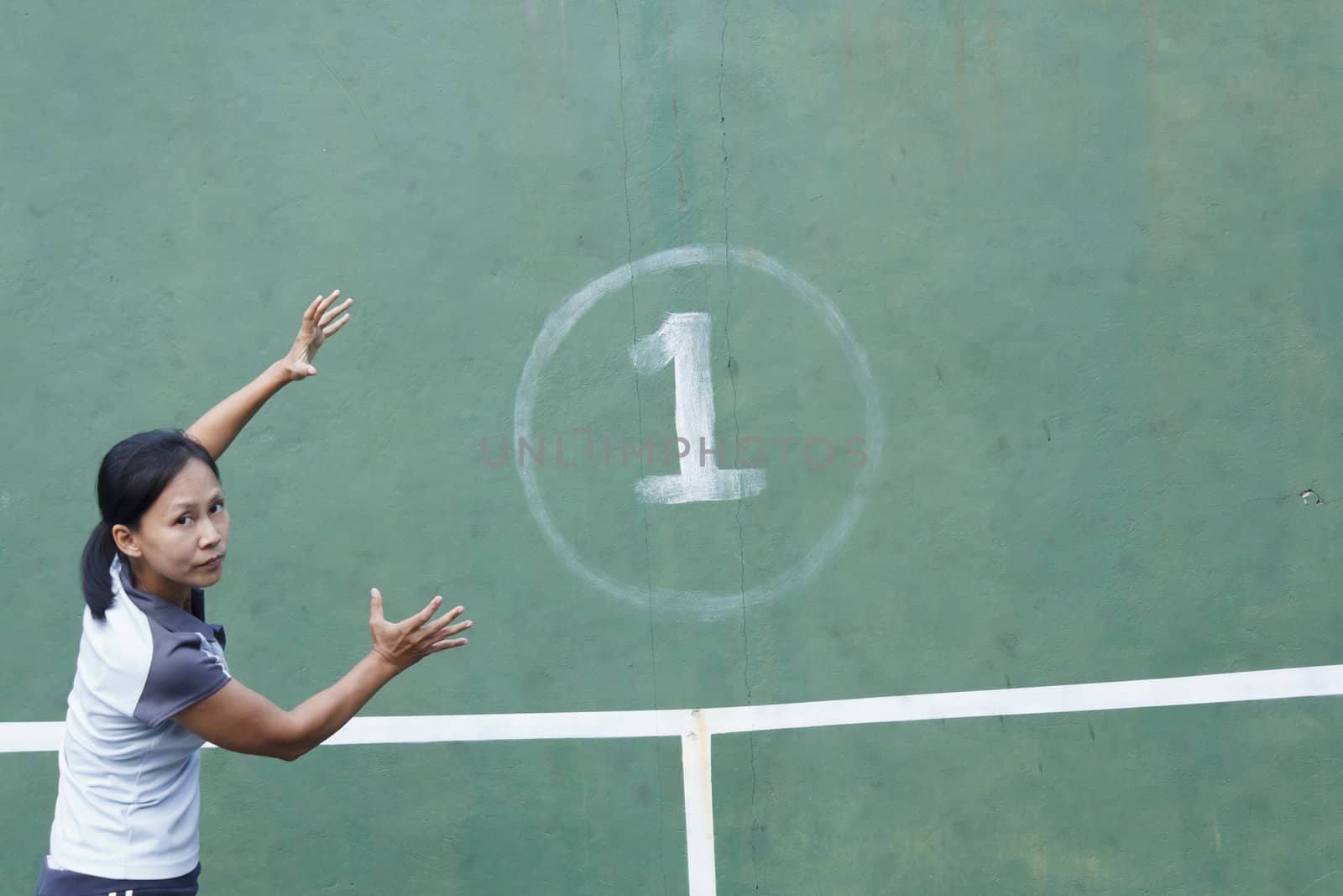 Female tennis player action hold number one at tennis practice wall