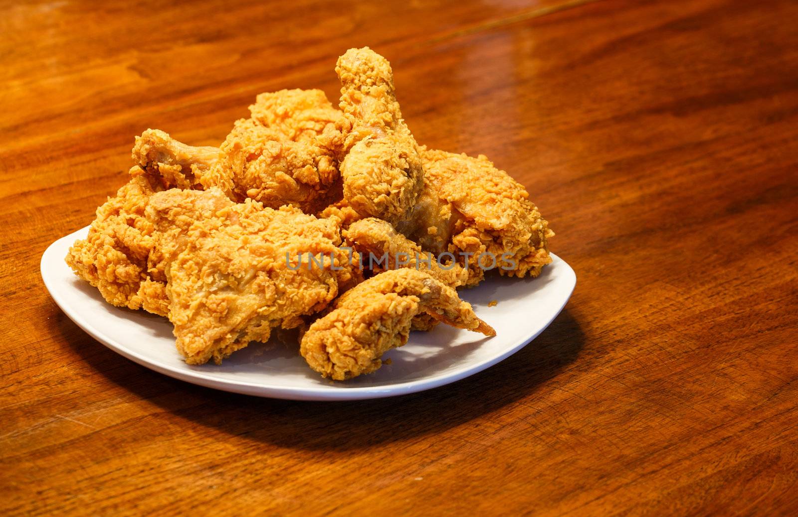 Fresh, fried chicken on a square white plate on a wood table