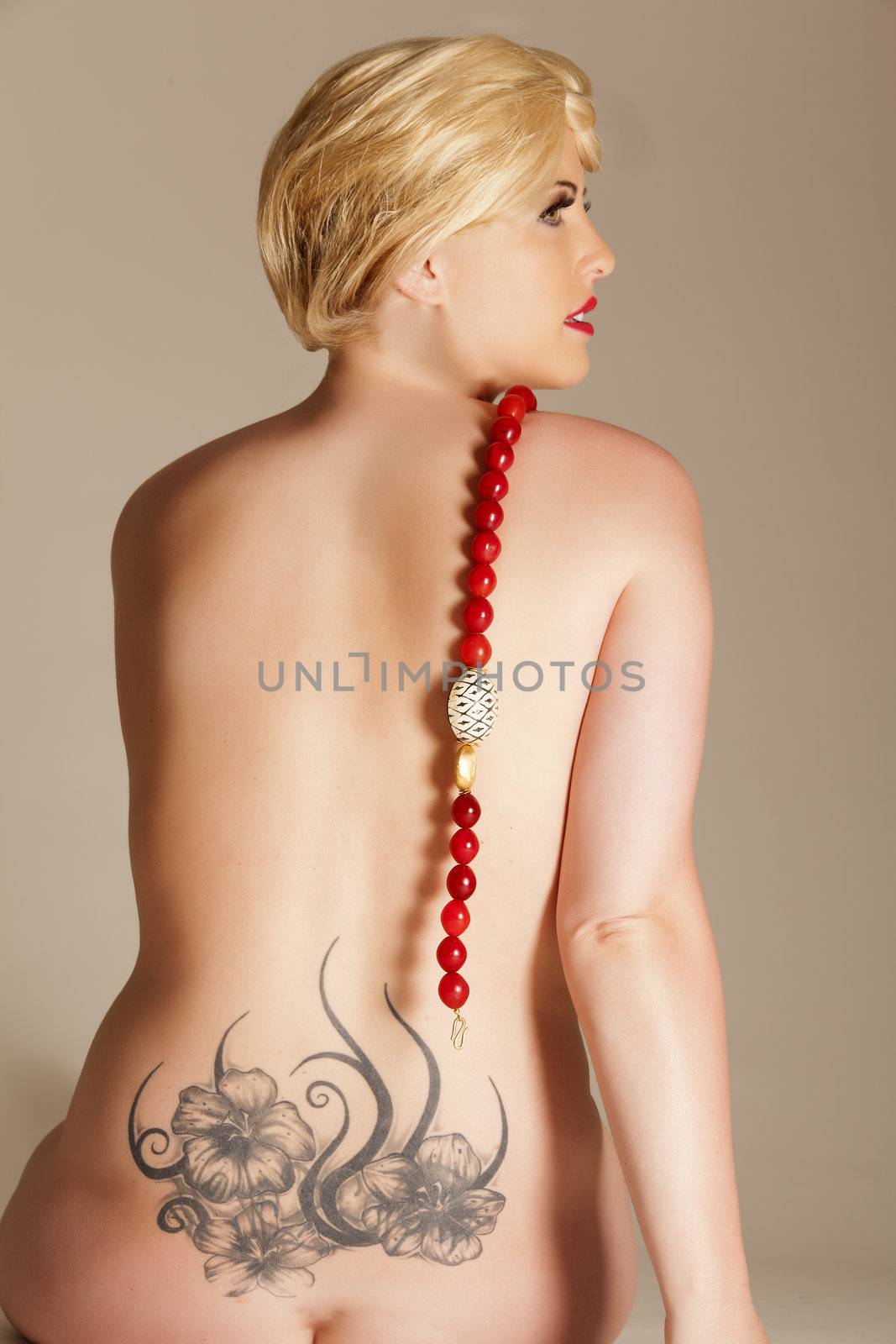 Naked woman from behind with a tattoo designer and chain