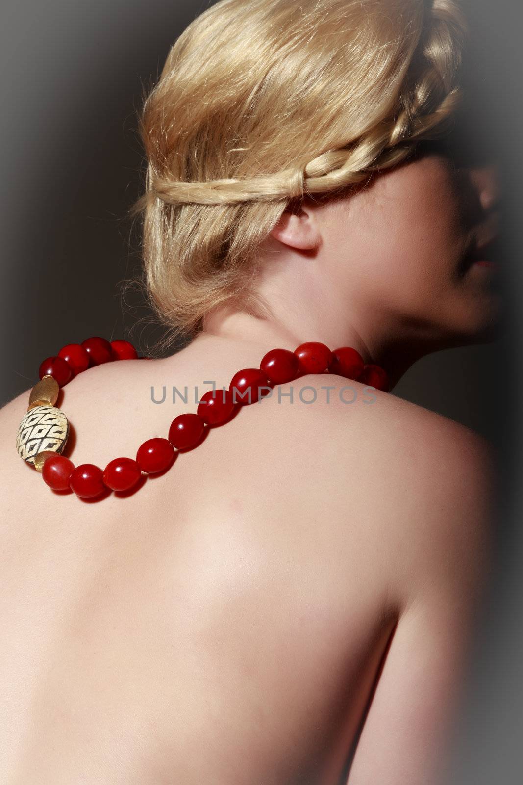 Blonde woman in covert act with a romantic hairstyle and designer necklace