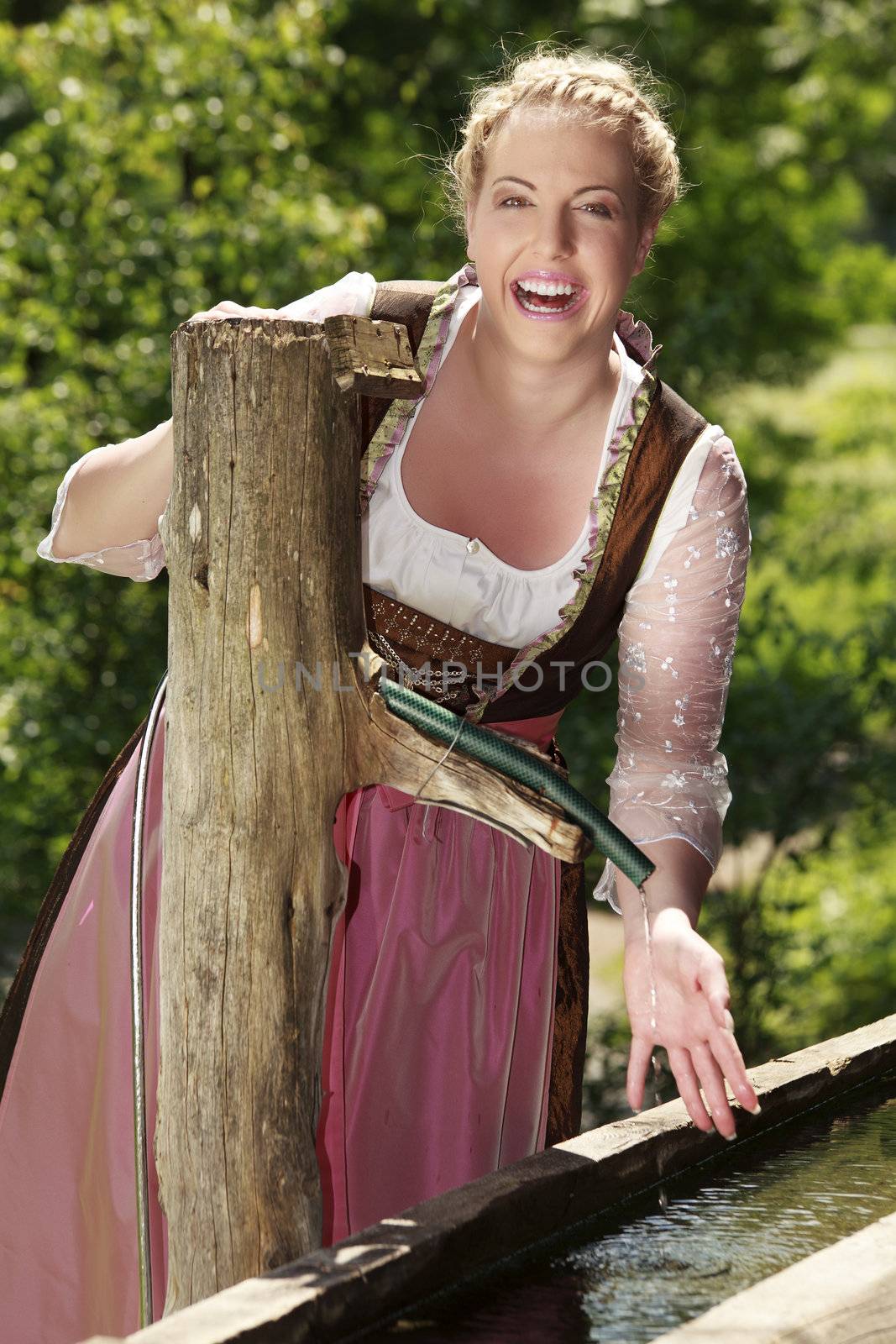 Laughing girls in Bavarian costume at a well
