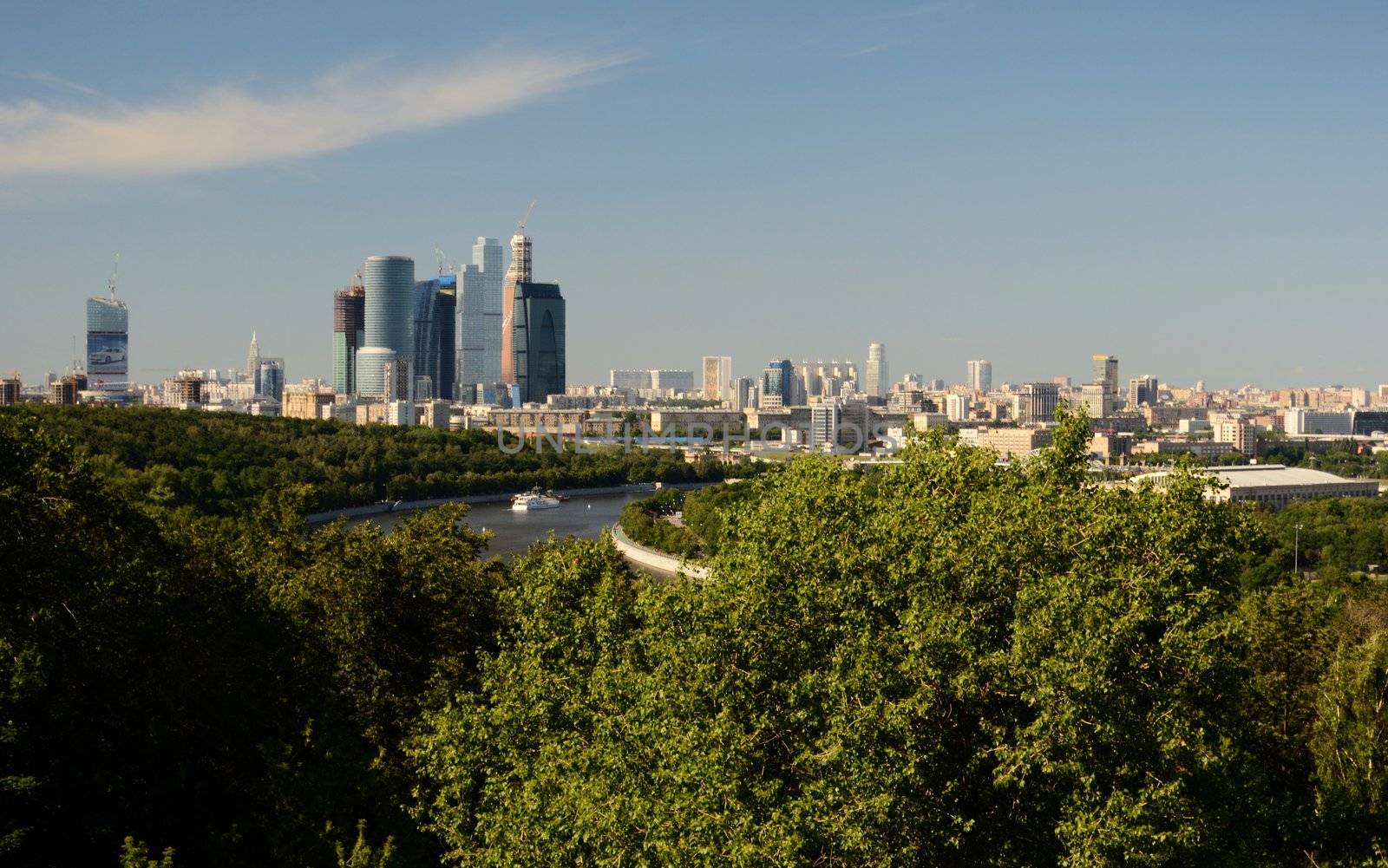 Summer sunny day view of Moscow with green trees, skyscrapers and blue sky