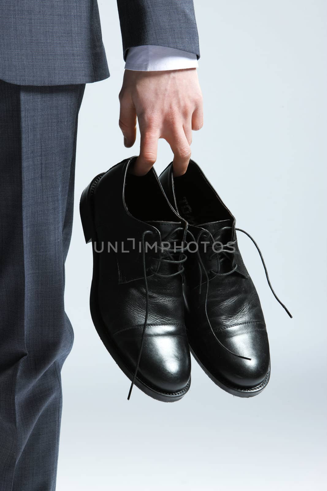 businessman holding the shoes in hand, close up