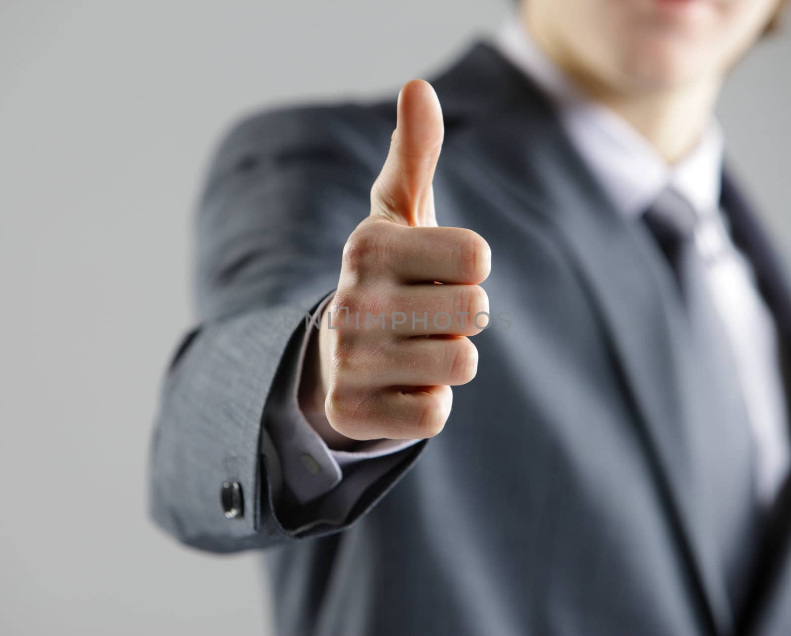 Close-up of a young businessman showing thumbs up. by stokkete