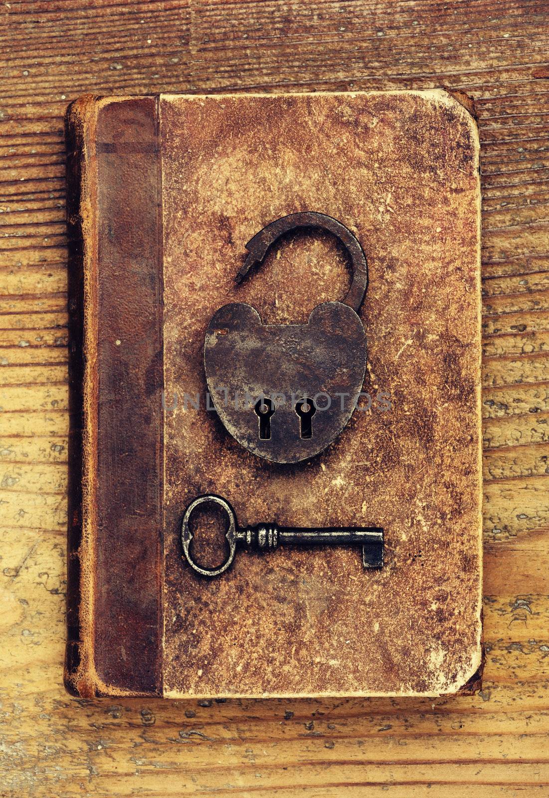 Antique Padlock with key on old book by stokkete