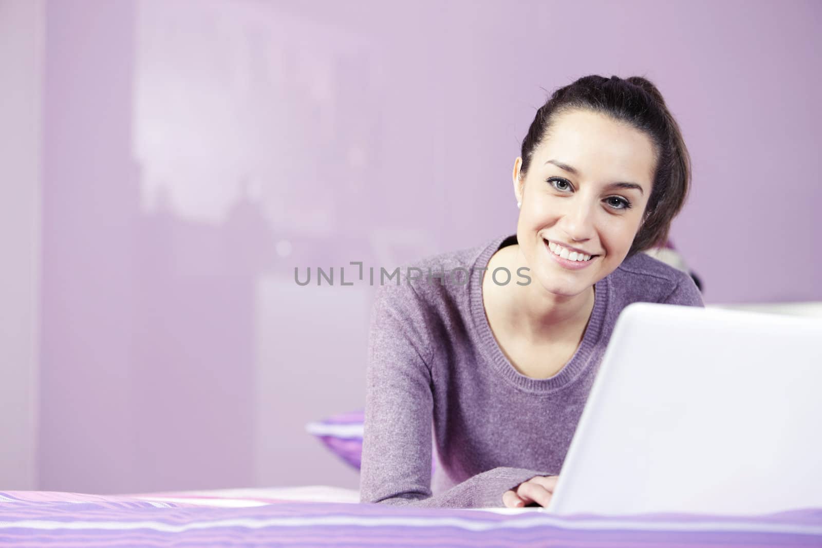 Portrait of a young female relaxing in bed while using laptop: c by stokkete