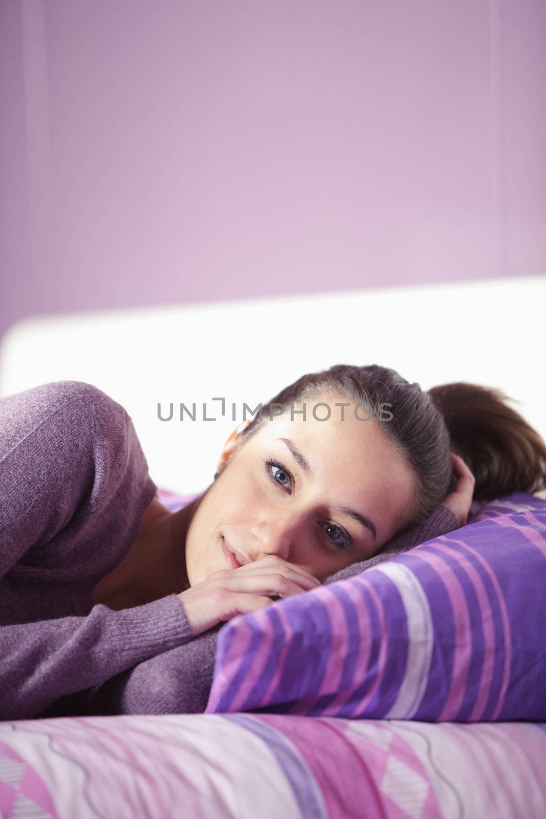 Closeup of a young woman lying on bed by stokkete