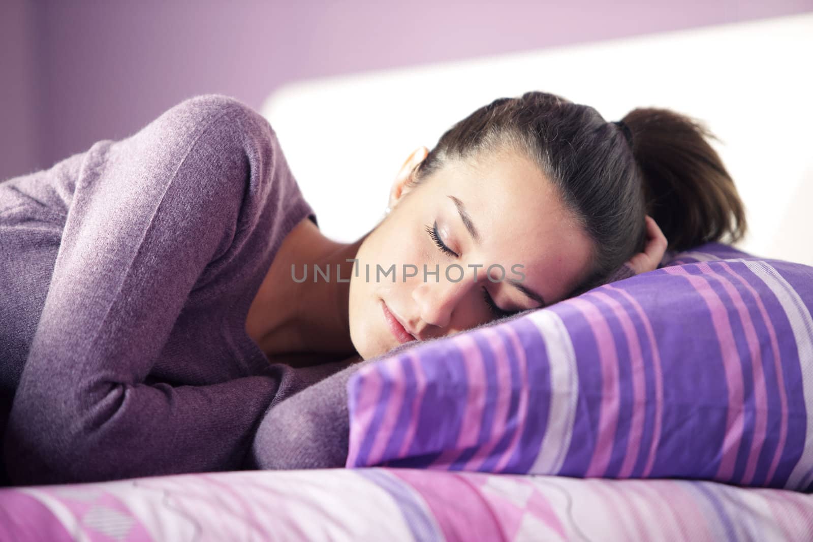 Close-up of an attractive young female sleeping in bed at home by stokkete