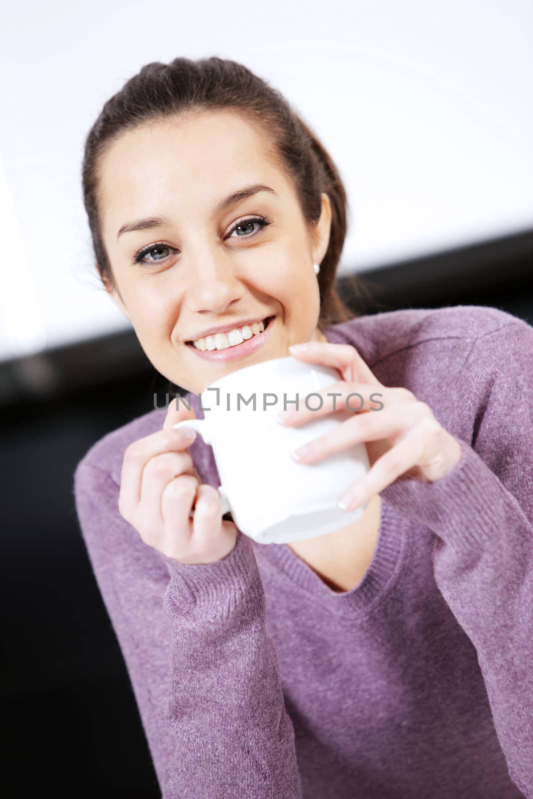 Beautiful young  woman having coffee while at the kitchen