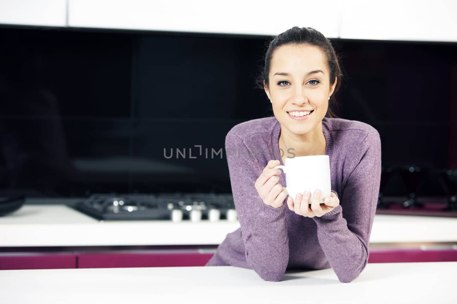 Beautiful young  woman having coffee while at the kitchen