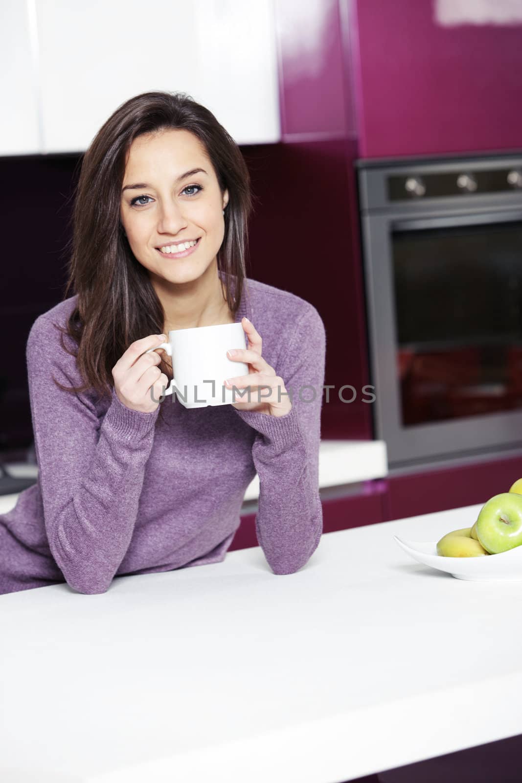 Beautiful young  woman having coffee while at the kitchen