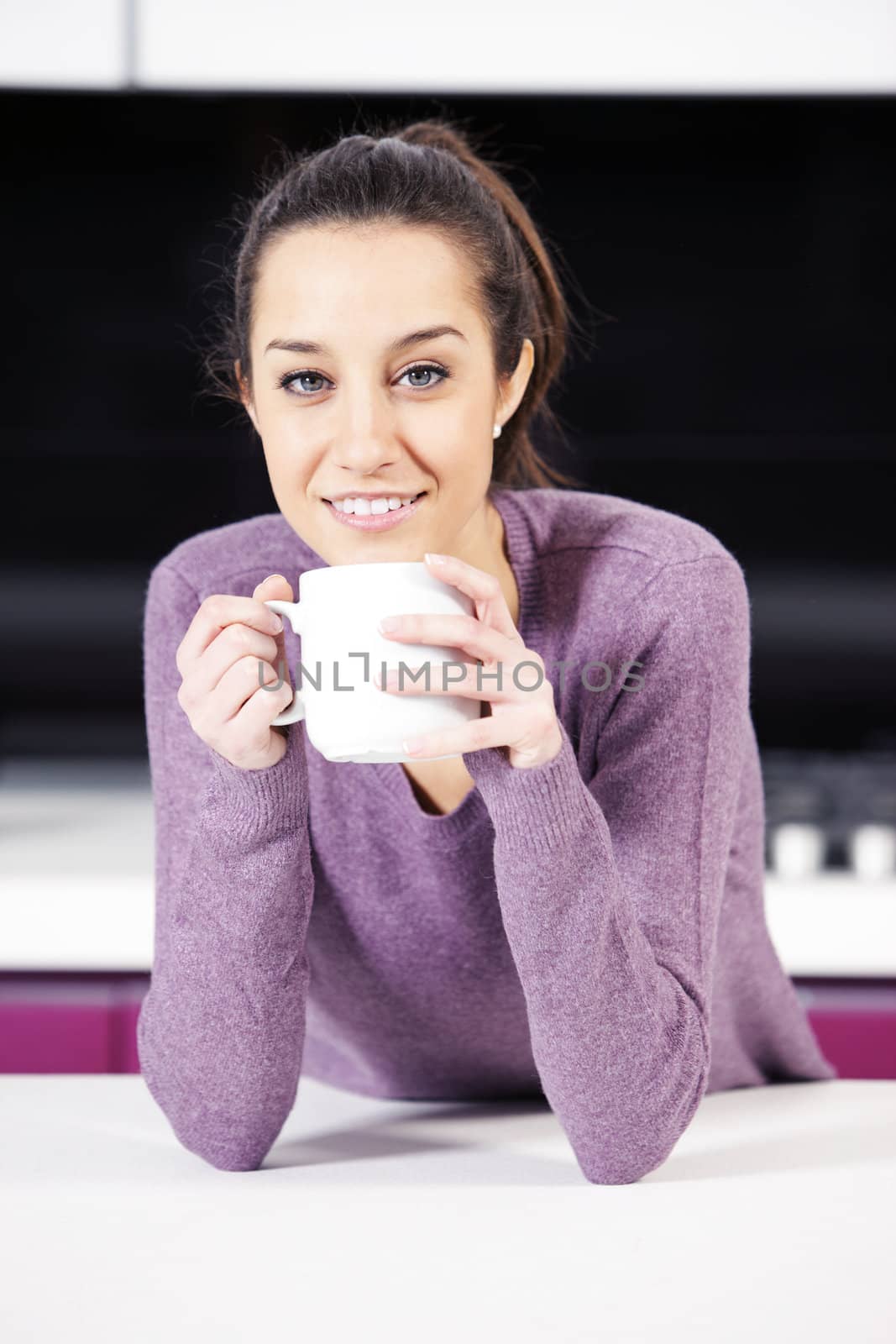 Beautiful young  woman having coffee while at the kitchen