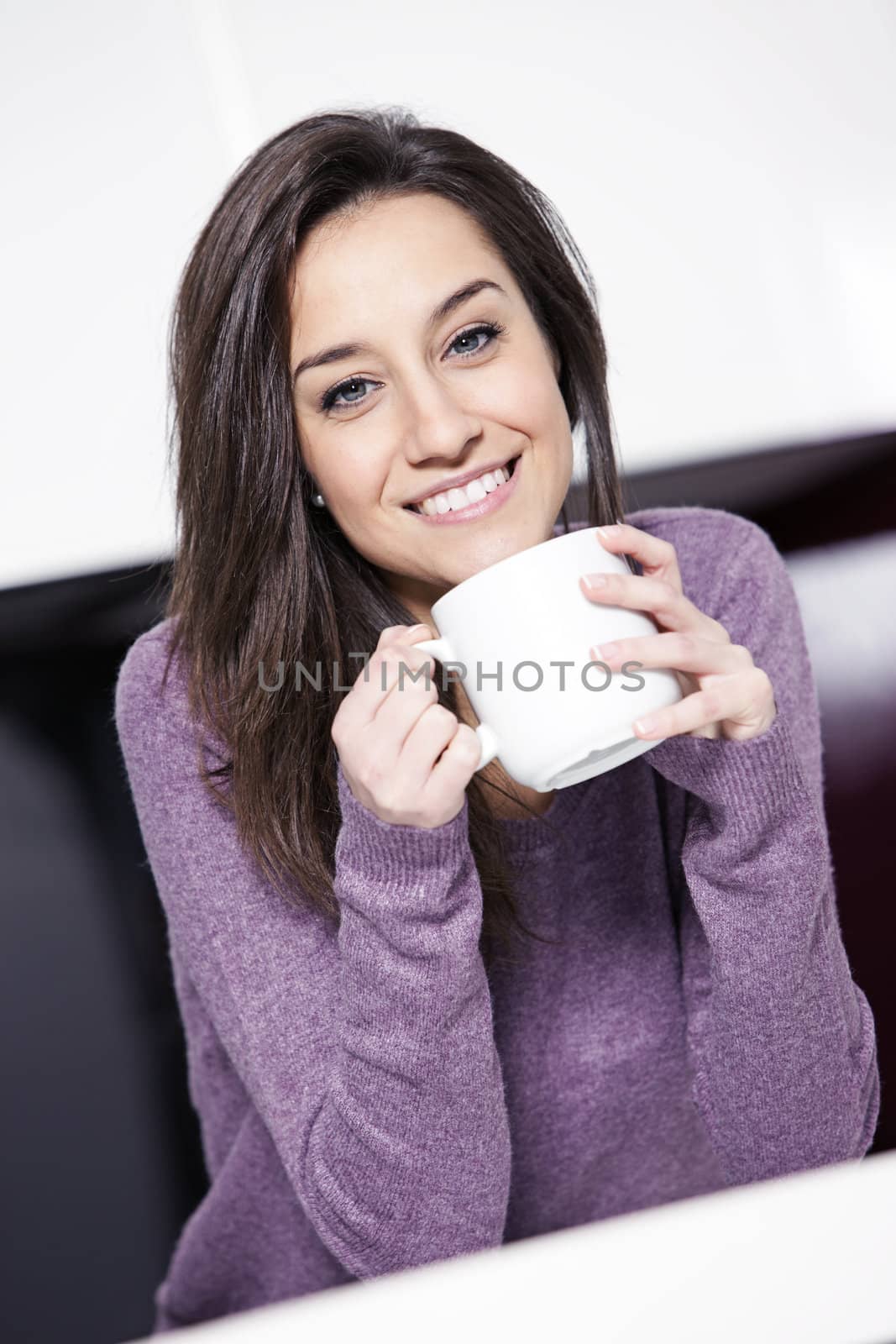 Beautiful young  woman having coffee while at the kitchen