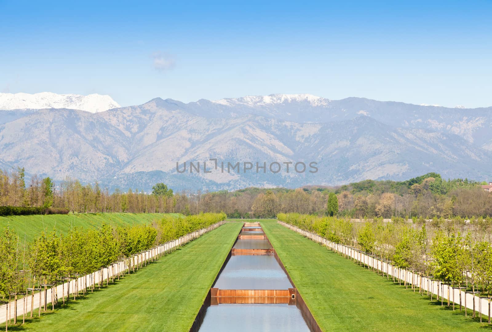 Italy - Water pool in green field with Alps mountains on background