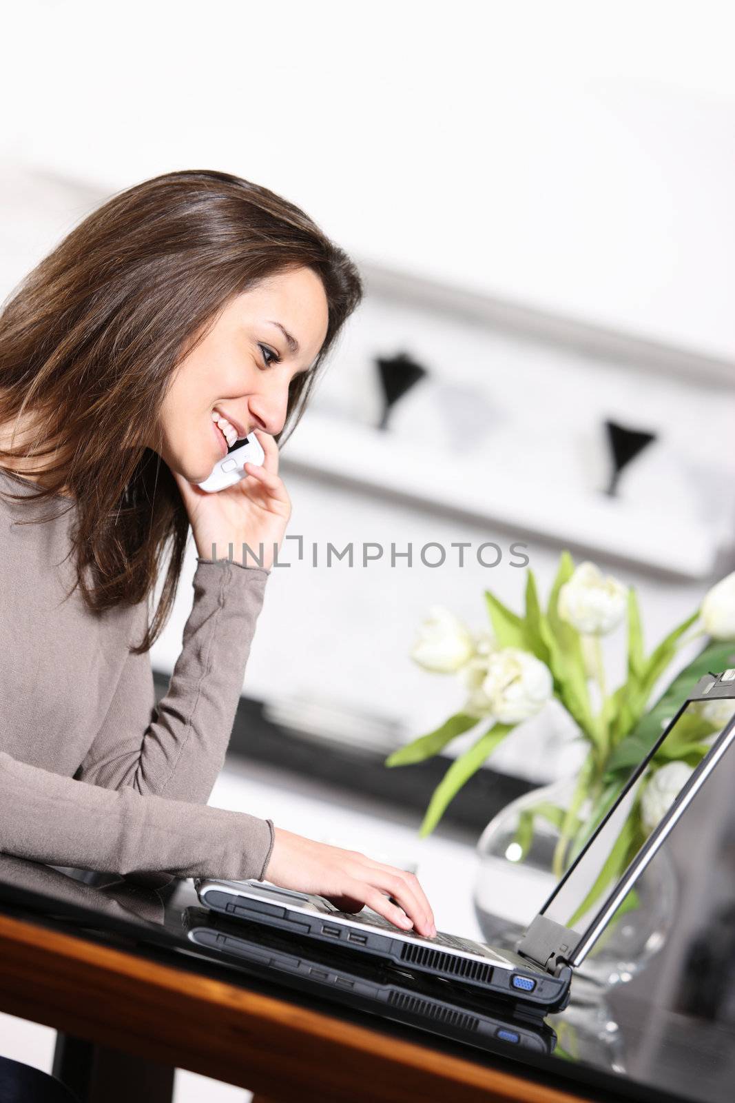 young woman with mobile phone  working on her laptop