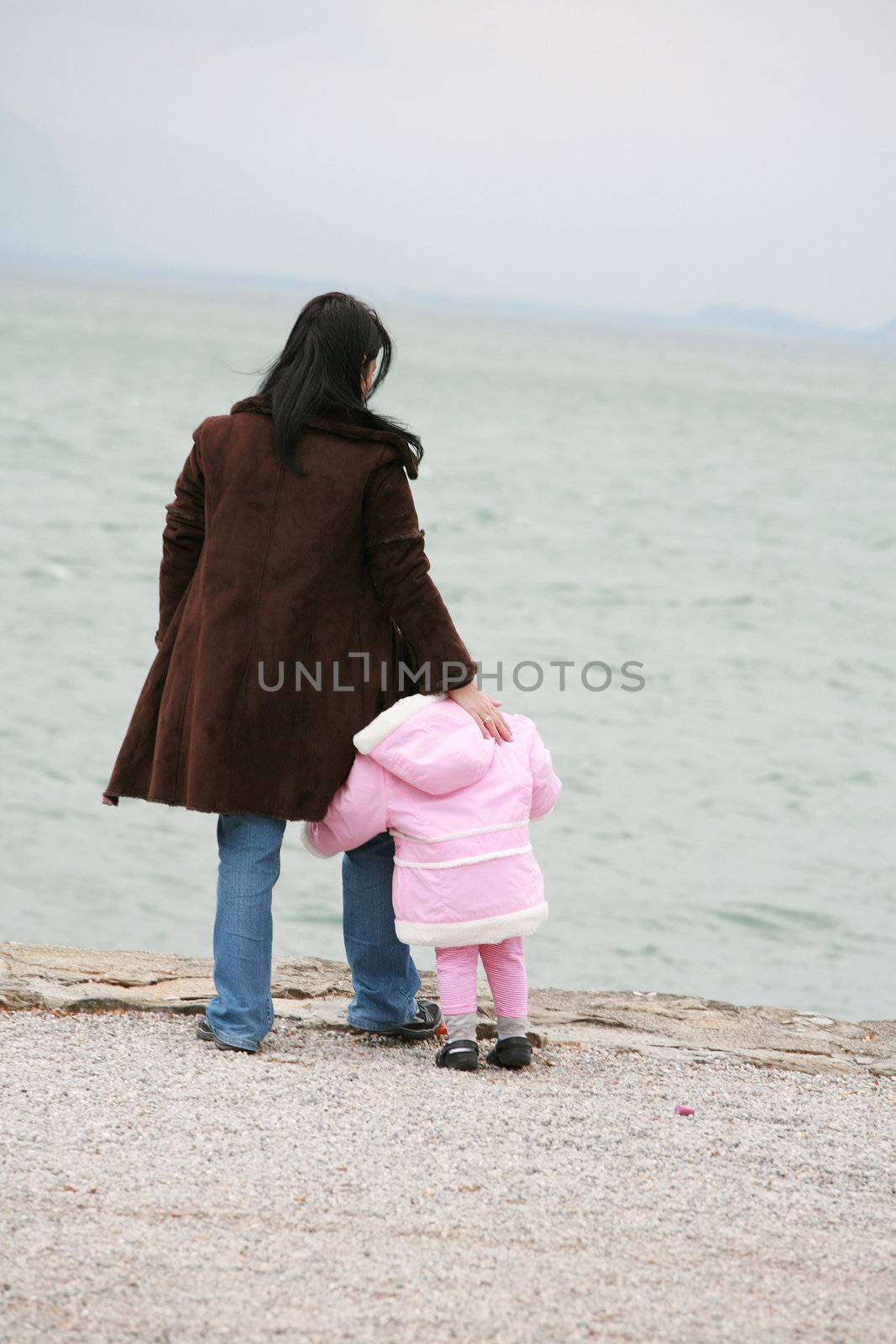 Mother and daughter looking the sea on winter by dacasdo