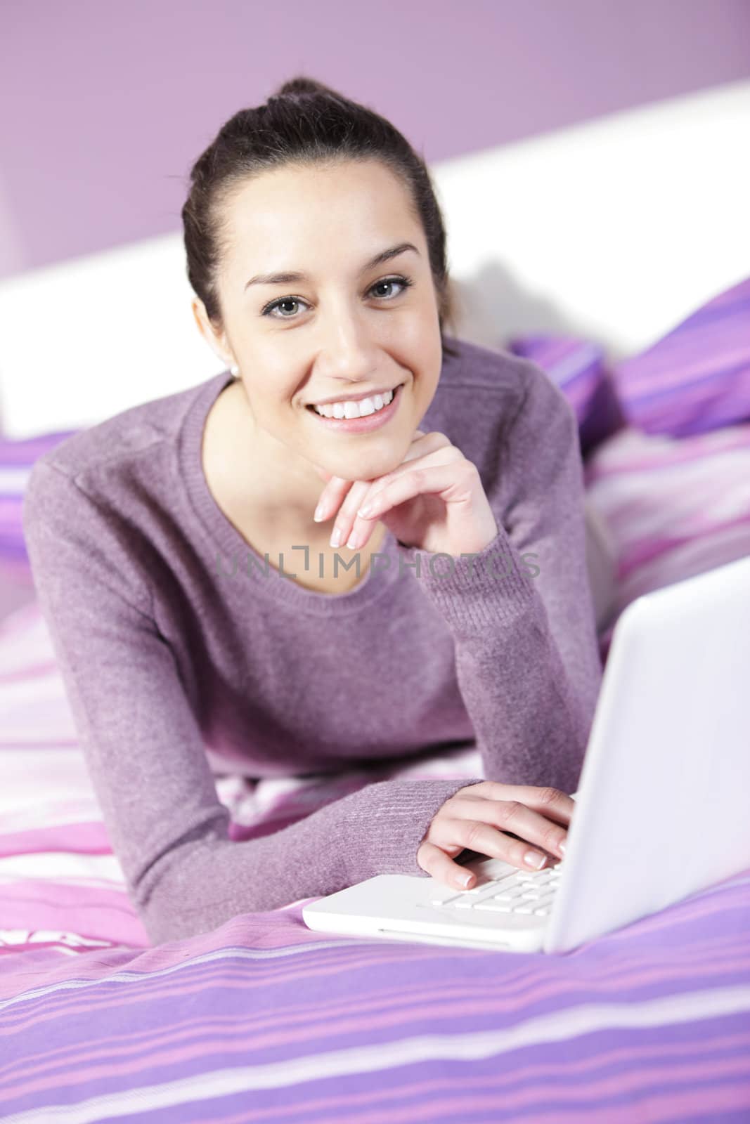 Portrait of a young female relaxing in bed while using laptop