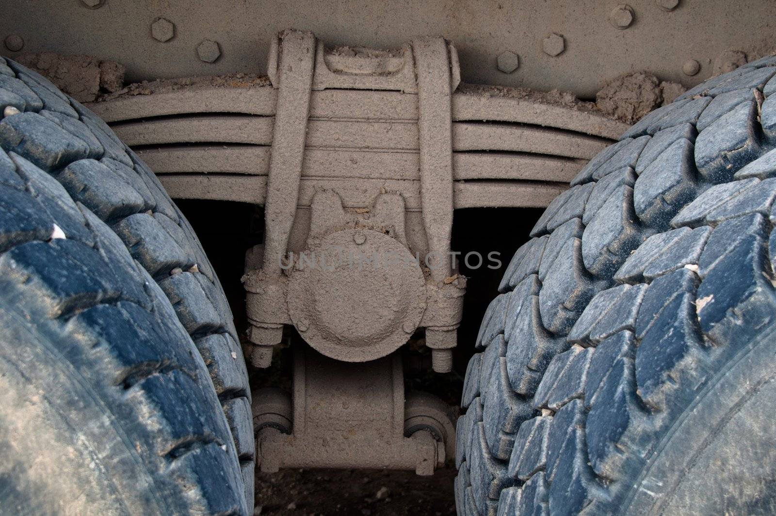 Suspension detail of leaf-spring with tires of a dirty heavy truck