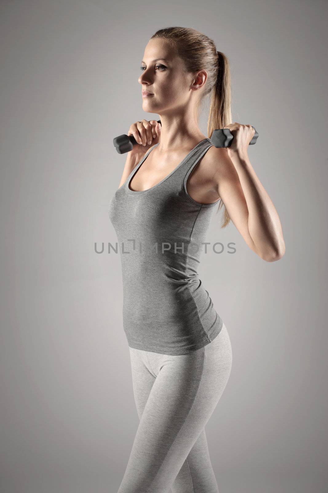 A beautiful woman raises with dumbbells 