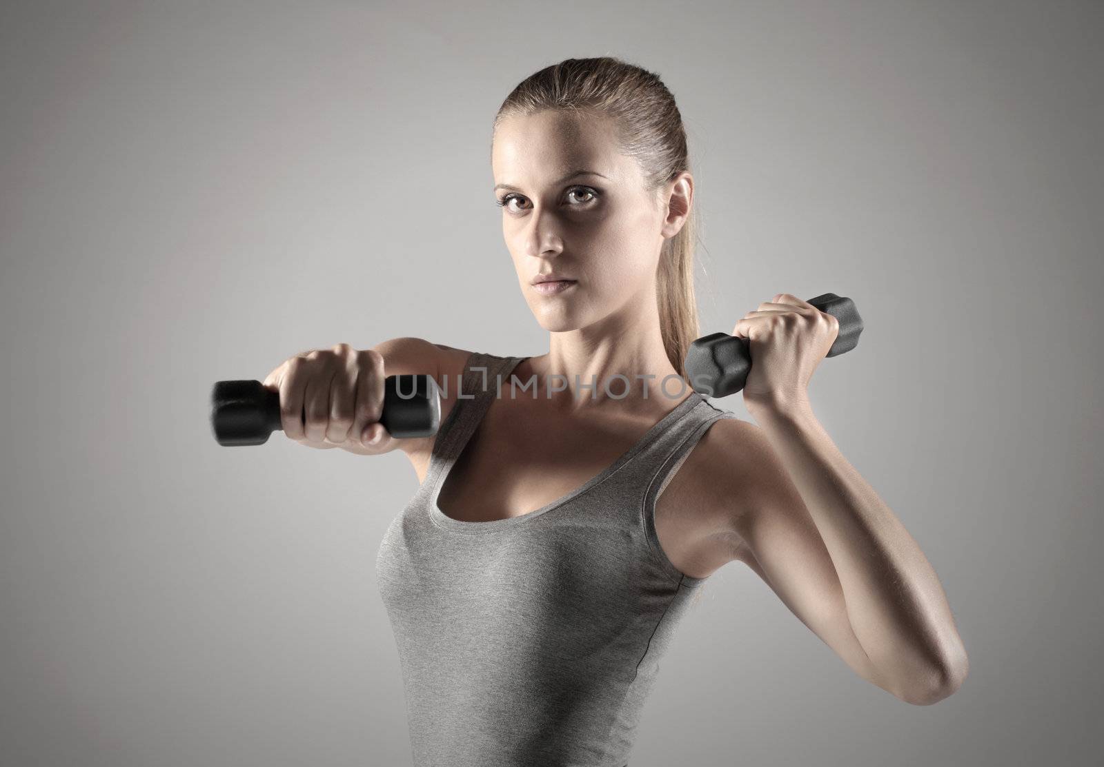 A beautiful woman raises with dumbbells 