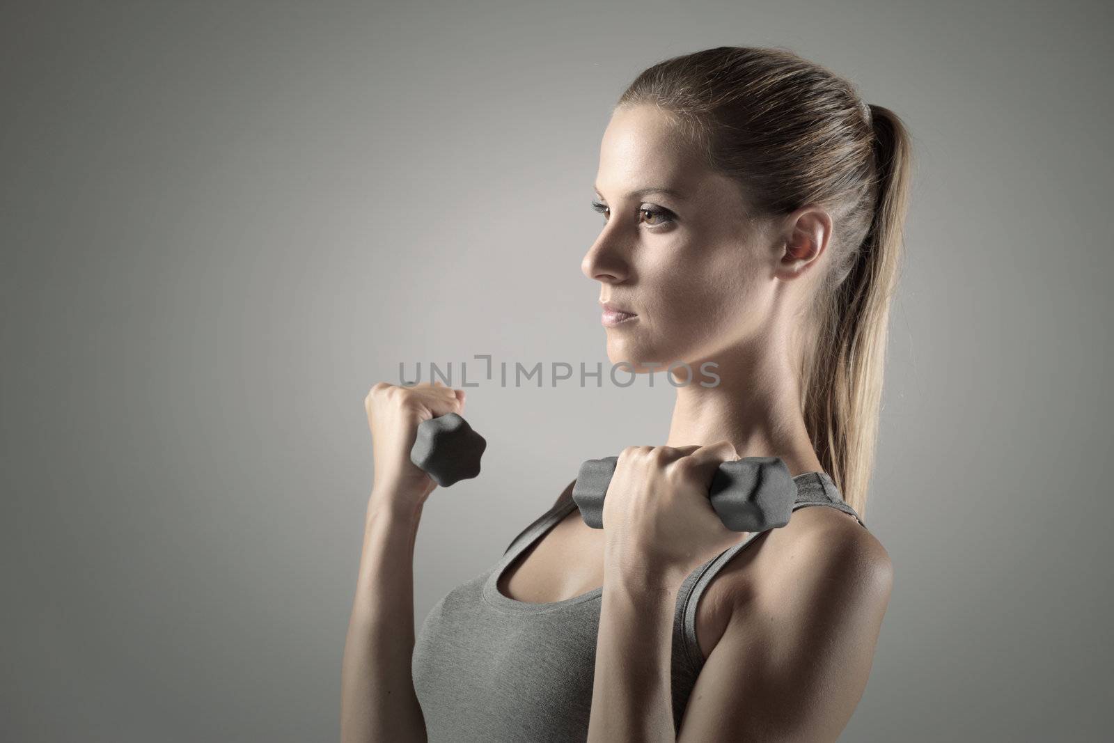 A beautiful woman raises with dumbbells 