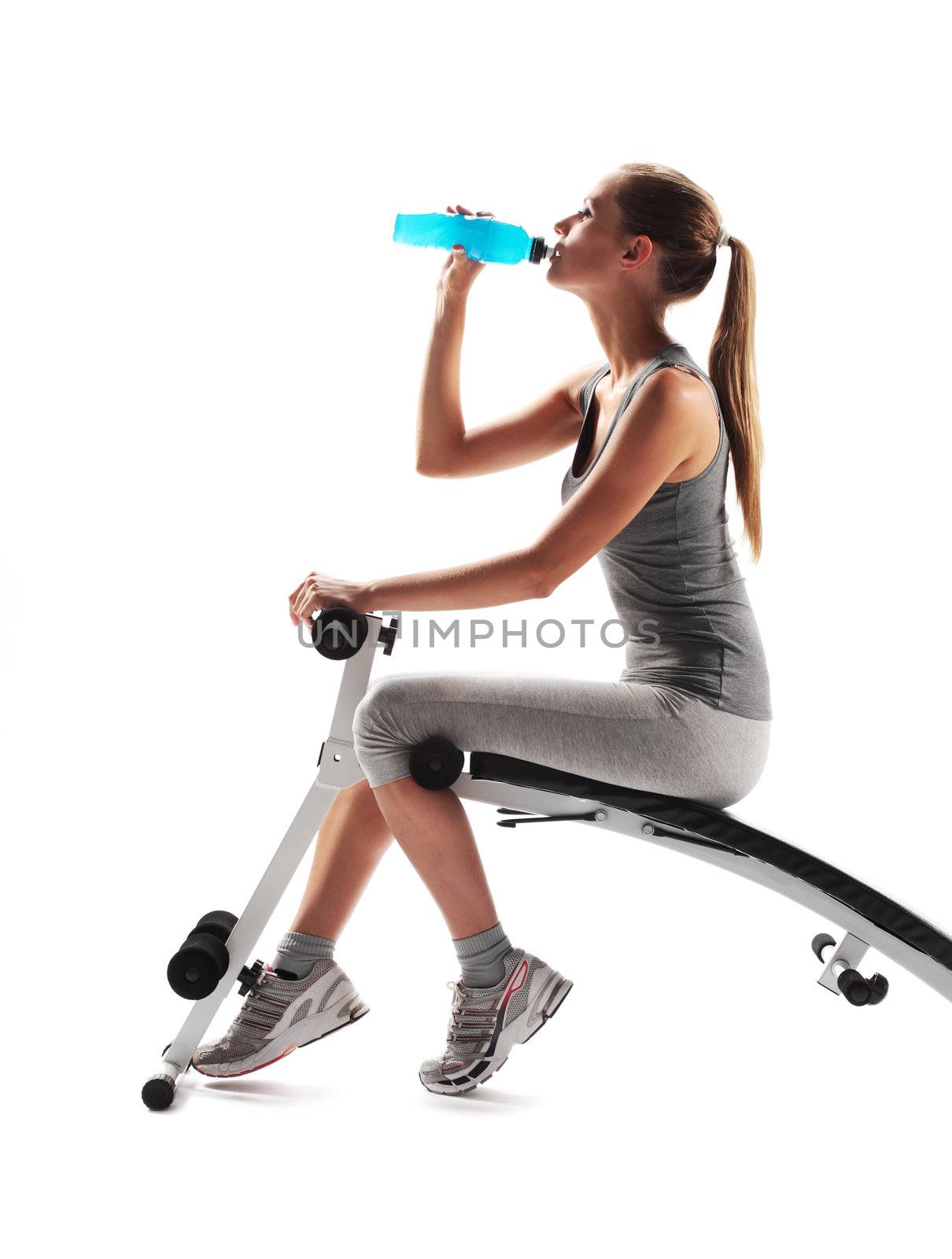 Thirsty young woman drinking after fitness workout.
