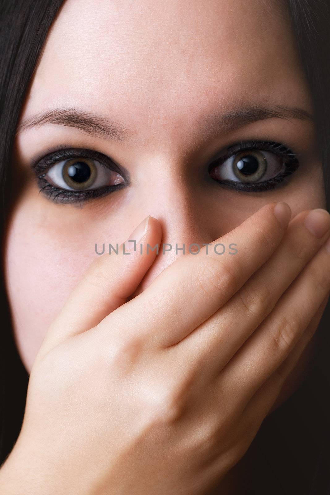closeup black haired girl covering the face with her hand
