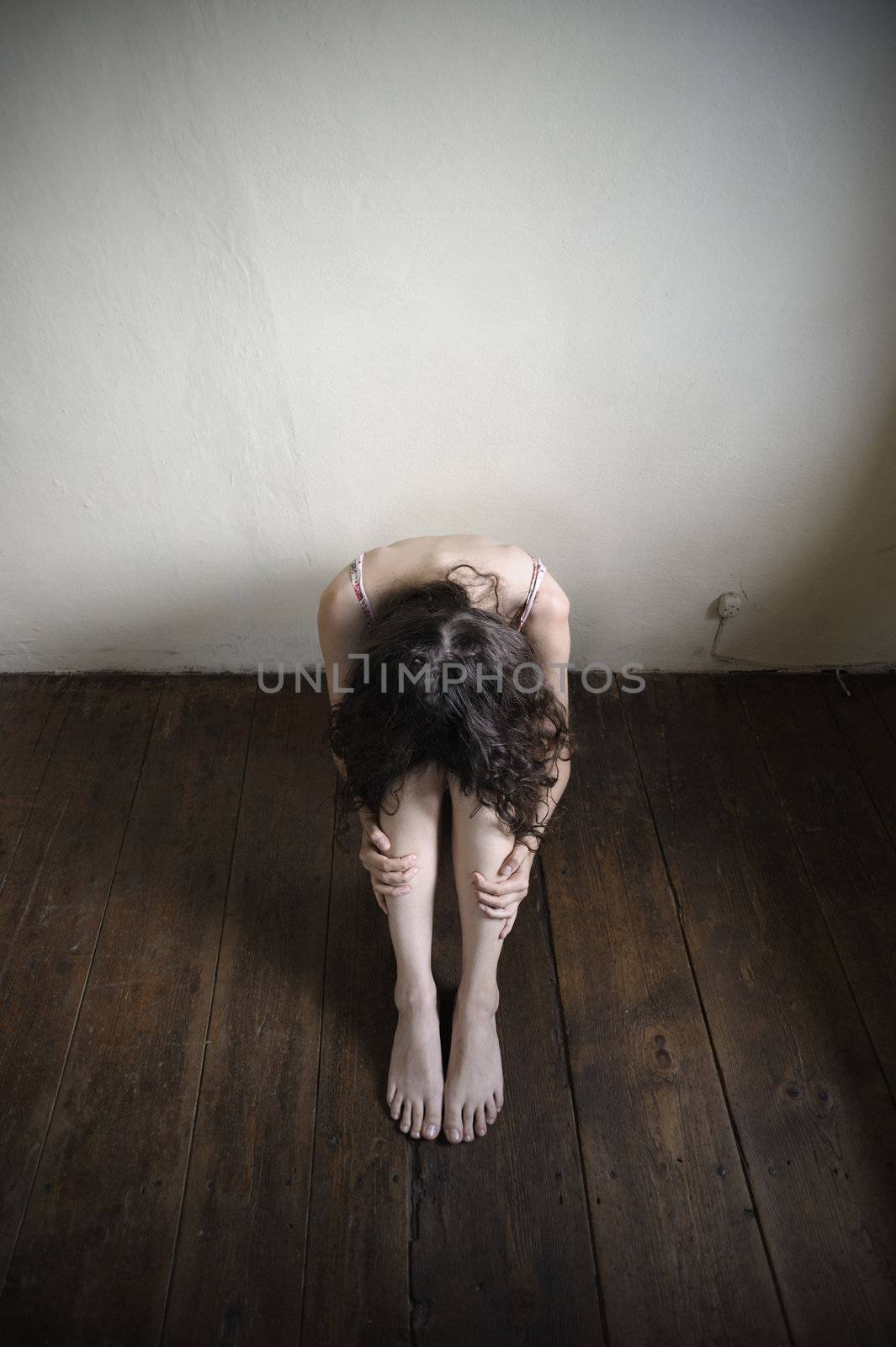 a desperate young woman is sitting on an old wooden floor. top view