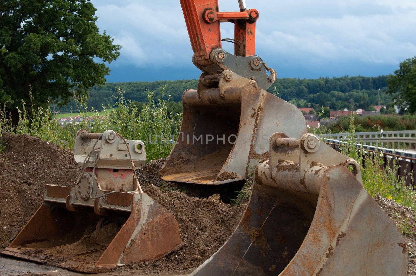 Excavator on construction site with different sized shovels