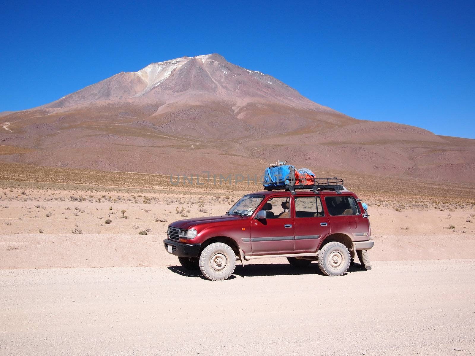 Four-wheel drive tourist vehicle used for a multiple day tourist tour in the Atacama desert in Bolivia in front of a volcano.