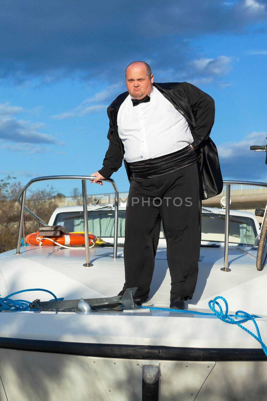 Overweight man in tuxedo standing on the deck of a luxury pleasure boat